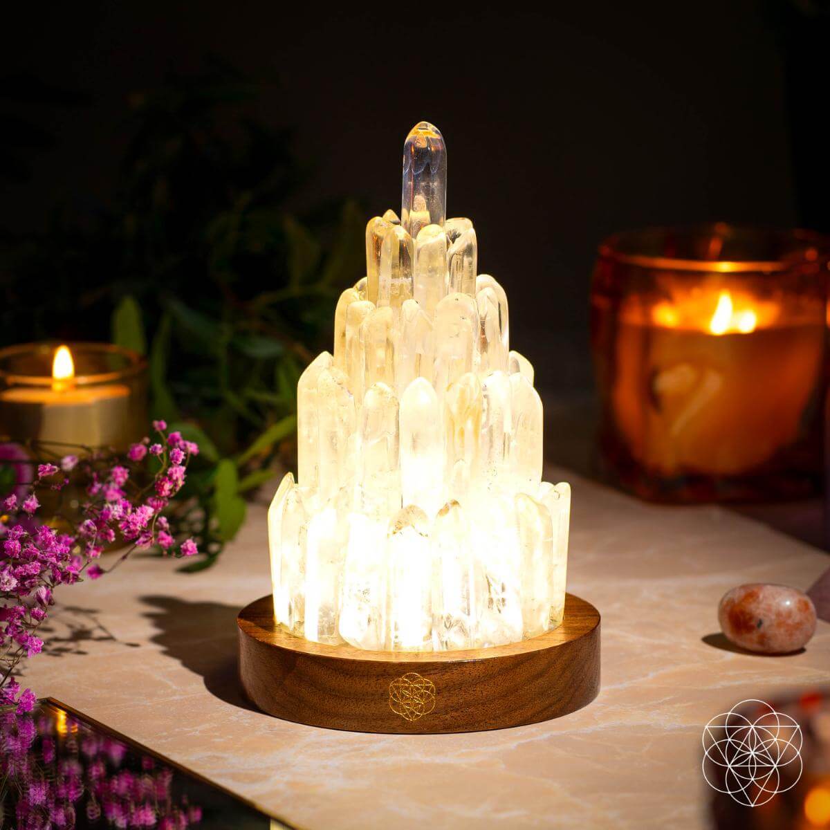 Clear Quartz Tower Lamp glowing with candles and flowers in calming wellness setting